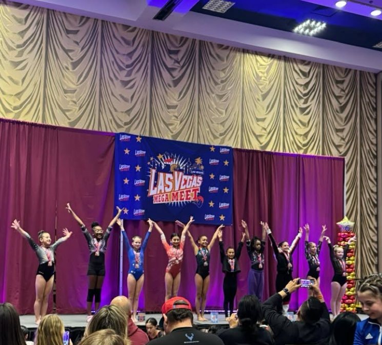 Athletes celebrating on the awards stage in front of the Las Vegas Mega Meet banner
